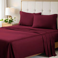 A neatly made bed styled with a burgundy 700 Thread Count Egyptian Cotton Sateen Bed Sheet Set, featuring smooth flat and fitted sheets alongside matching pillows
