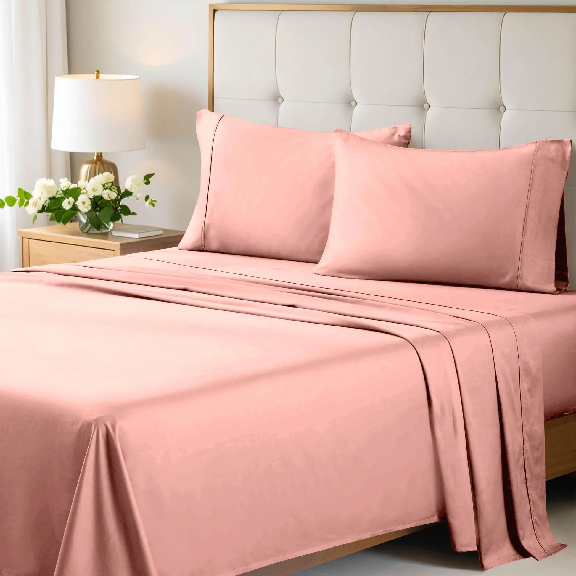 A neatly made bed styled with a pink 700 Thread Count Egyptian Cotton Sateen Bed Sheet Set, featuring smooth flat and fitted sheets alongside matching pillows
