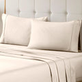 A neatly made bed styled with an ivory 700 Thread Count Egyptian Cotton Sateen Bed Sheet Set, featuring smooth flat and fitted sheets alongside matching pillows