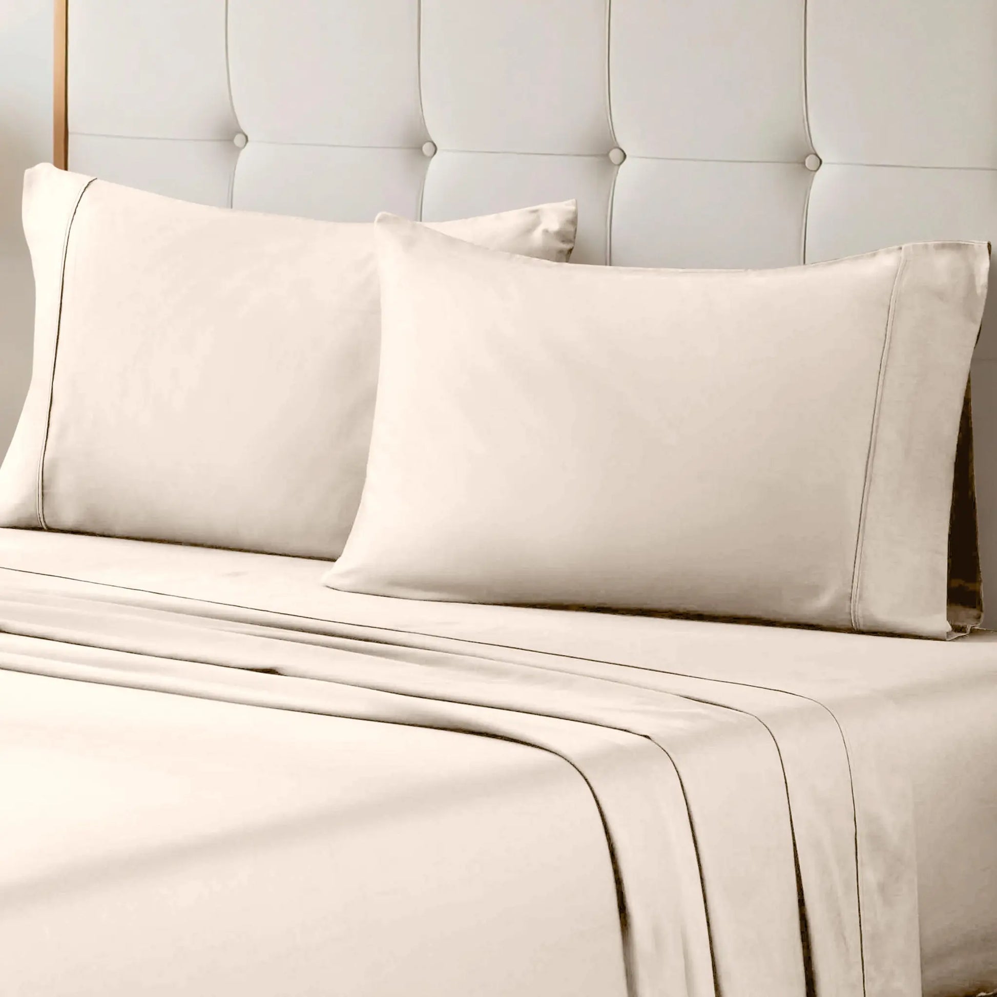 A neatly made bed styled with an ivory 700 Thread Count Egyptian Cotton Sateen Bed Sheet Set, featuring smooth flat and fitted sheets alongside matching pillows