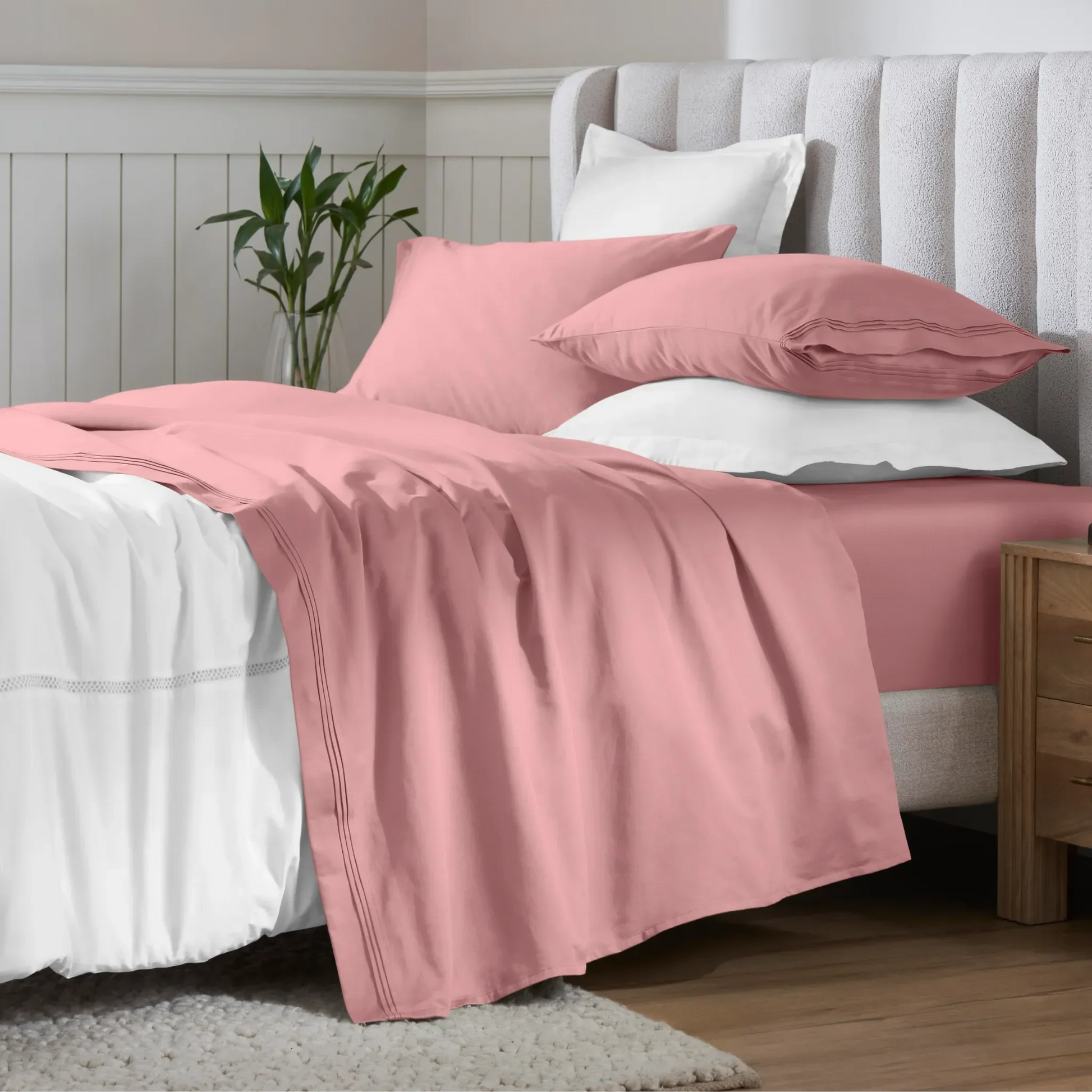 Blush pink 650 thread count Egyptian cotton sateen sheets arranged on a modern bed with coordinating pillows.