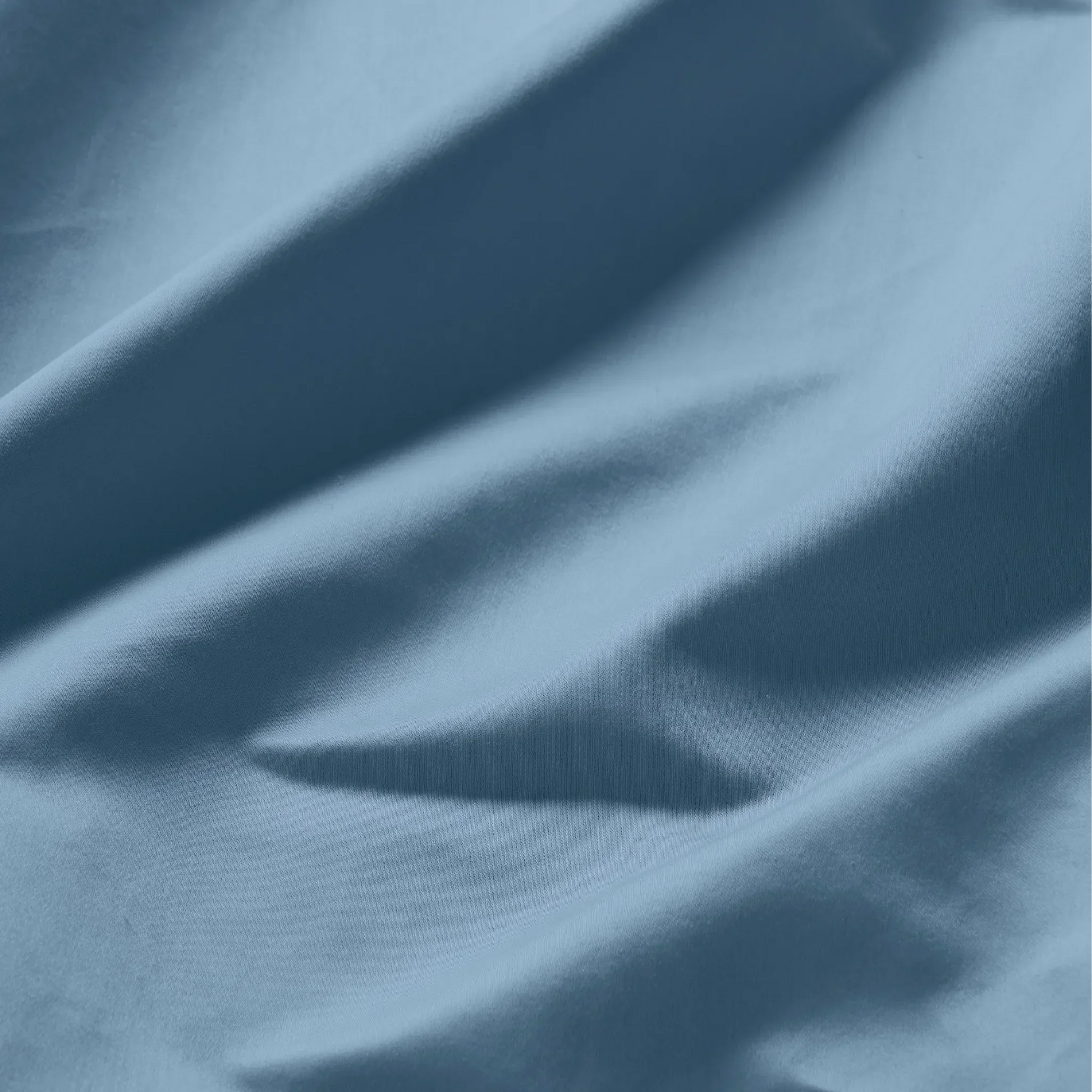 Close-up texture shot of soft medium blue Egyptian cotton sateen fabric with natural folds