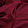 Close-up texture view of smooth, draped burgundy 300 thread count modal sheets made from beechwood