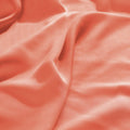 Close-up texture view of smooth, draped coral 300 thread count modal sheets made from beechwood