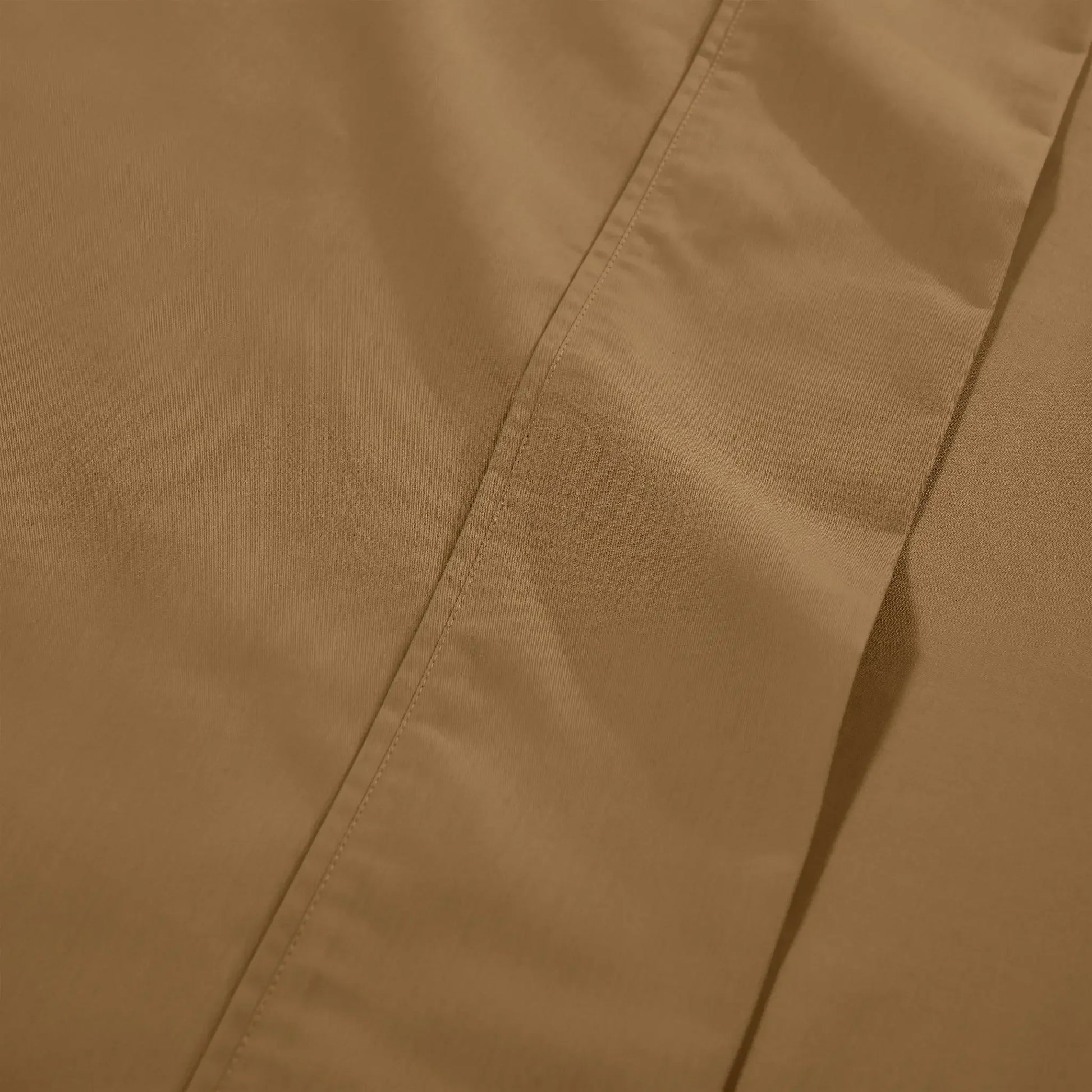 Extreme close-up macro shot of taupe brown cotton blend fabric showing fine weave texture and subtle hem stitching