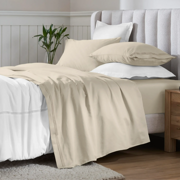 Ivory 650 thread count Egyptian cotton sateen sheets arranged on a modern bed with coordinating pillows