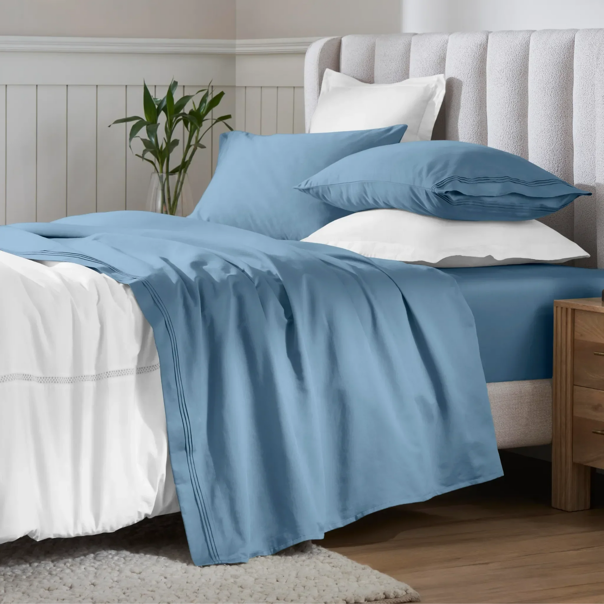 Medium blue 650 thread count Egyptian cotton sateen sheets arranged on a modern bed with coordinating pillows.