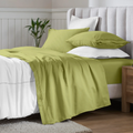 Olive green 650 thread count Egyptian cotton sateen sheets arranged on a modern bed with coordinating pillows.