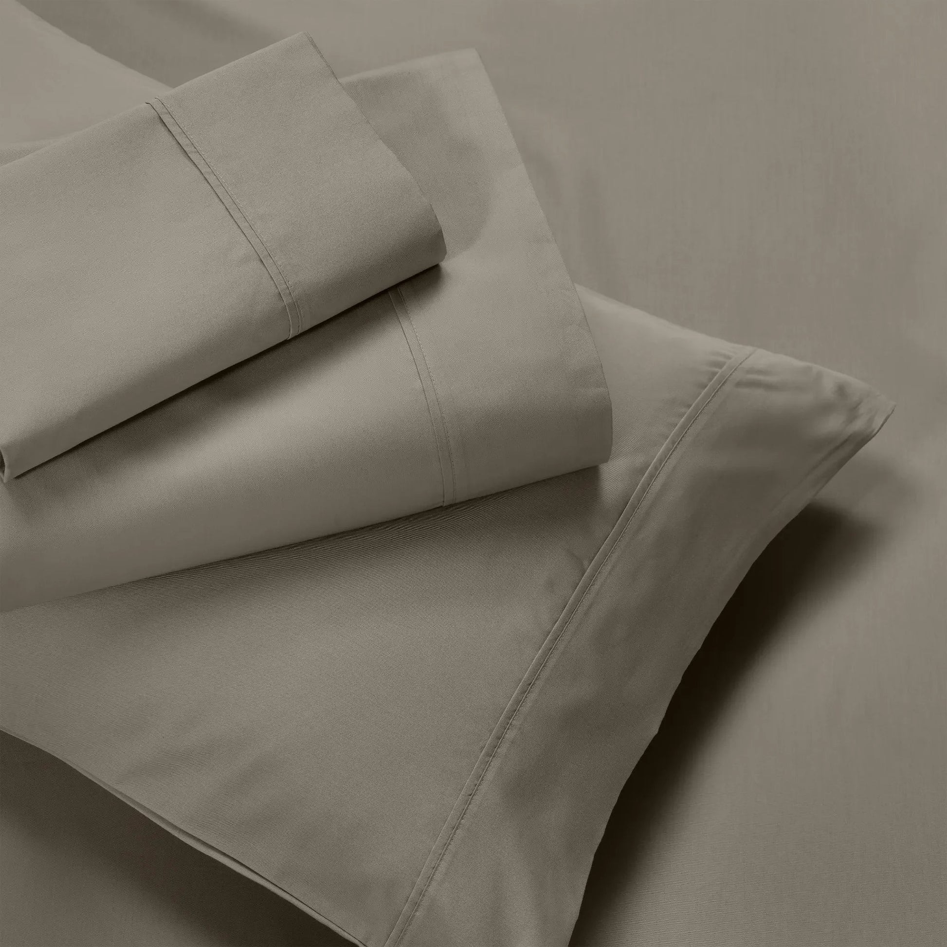 Overhead view of folded dark grey cotton blend bed sheets and matching grey pillowcase layout