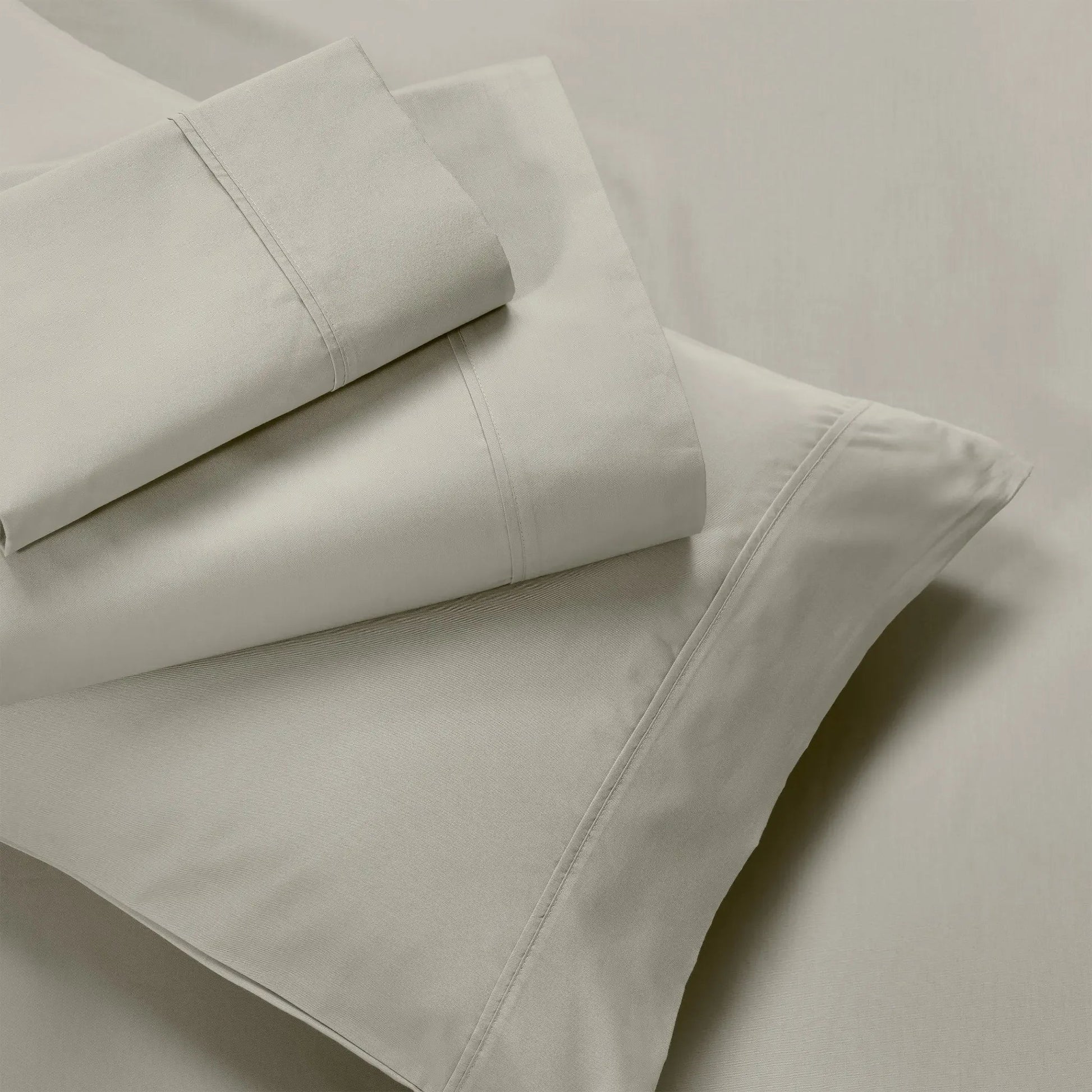Overhead view of folded stone gray cotton blend bed sheets and matching stone pillowcase layout.