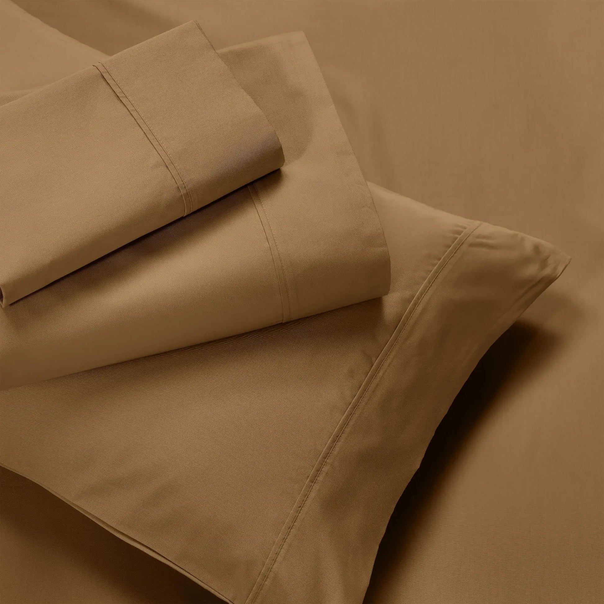 Overhead view of folded taupe brown cotton blend bed sheets and matching pillowcase layout