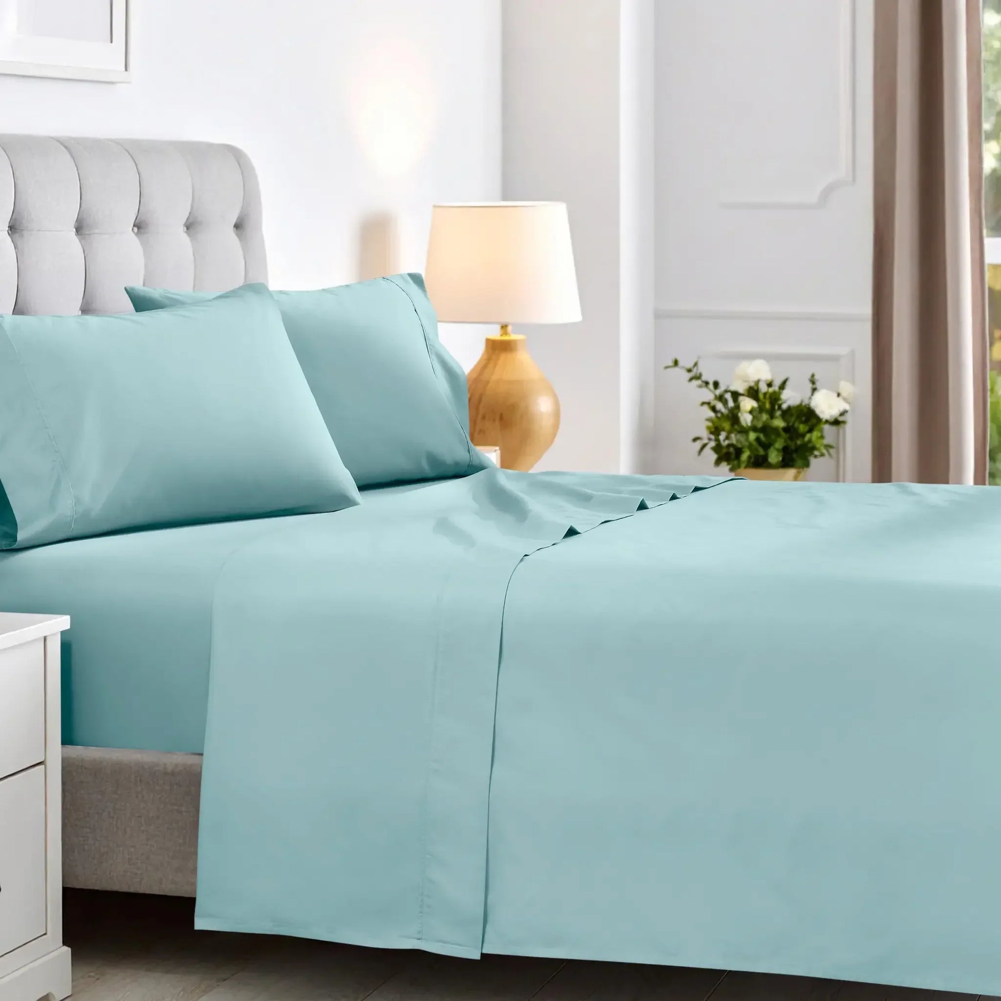 Solid light blue 600 thread count cotton blend deep pocket bed sheets on a bed with a tufted gray headboard