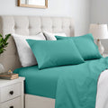 Solid teal deep pocket bed sheets and matching pillowcases with a tufted cream headboard