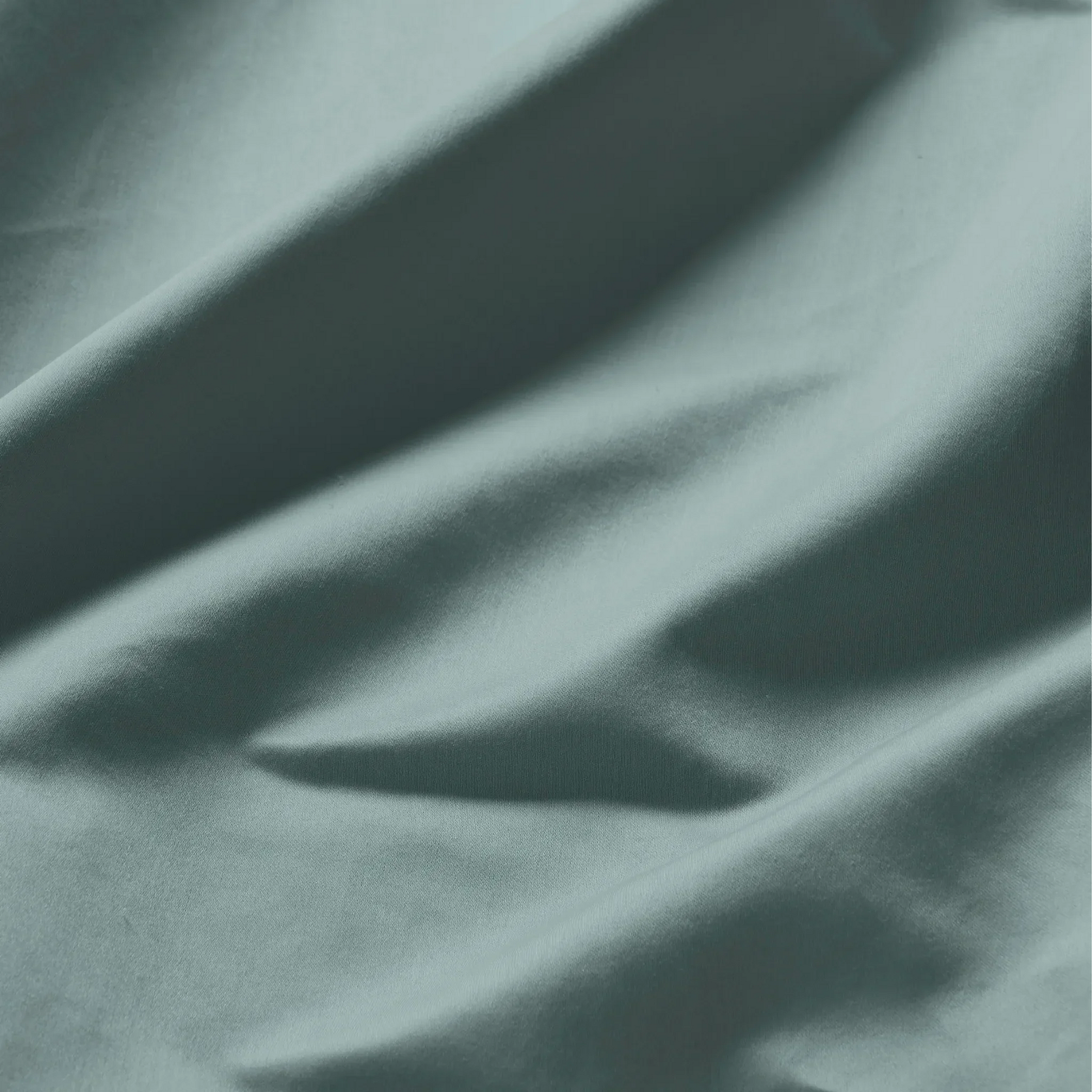 Close-up of smooth Teal blue Egyptian cotton fabric with a lustrous sateen weave and soft drape.