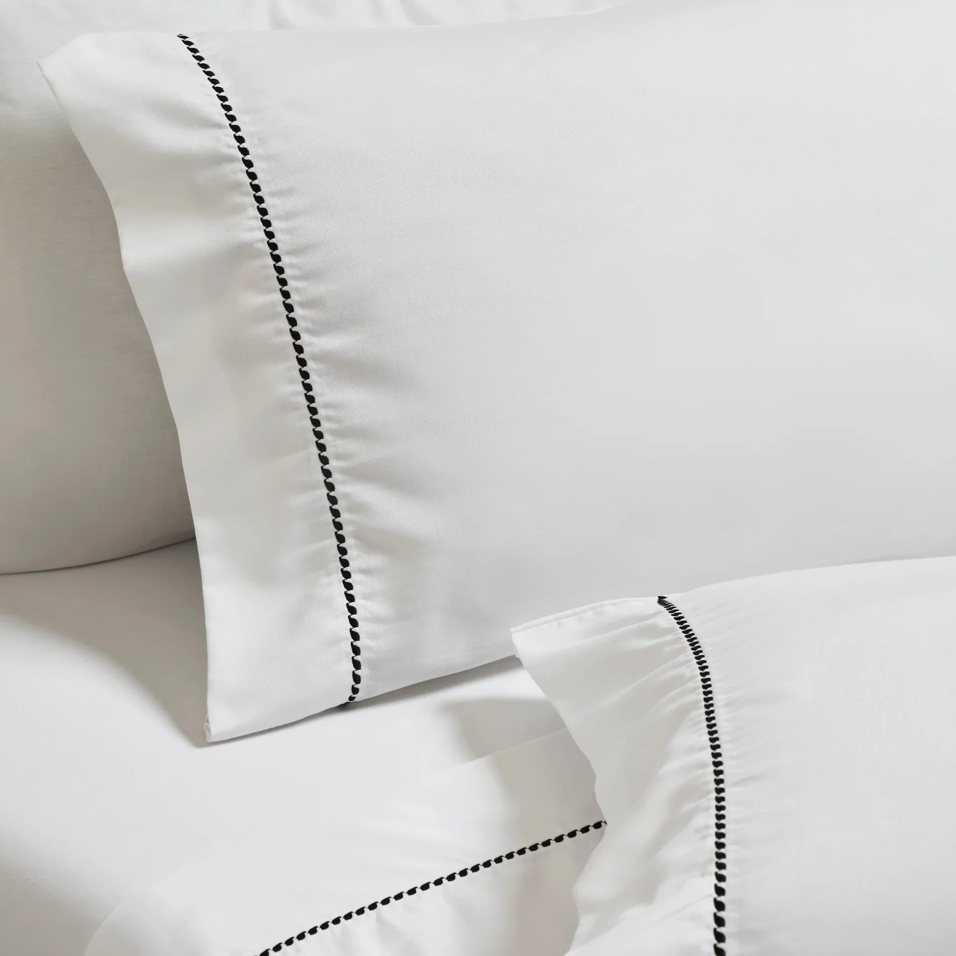 White/Black Imperia embroidered hem pillowcase set close-up detail.