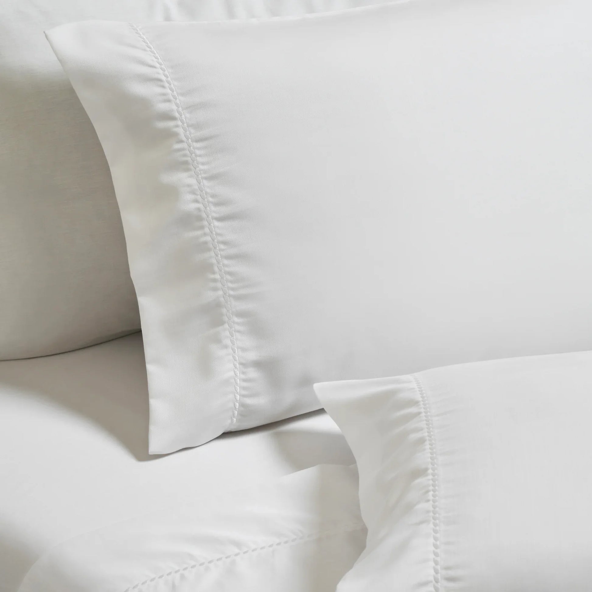 White Imperia embroidered hem pillowcase set close-up detail.